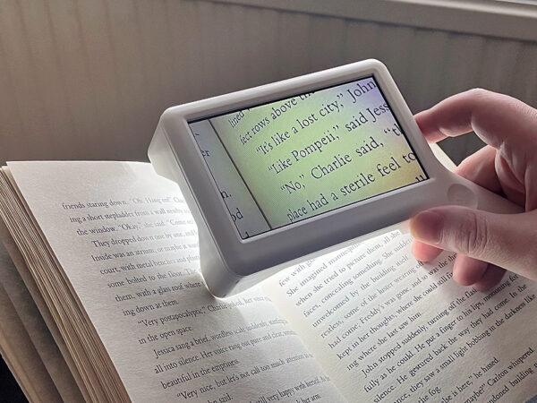 A rectangular screen is above a book, the text of the book is shown on the screen but is enlarged