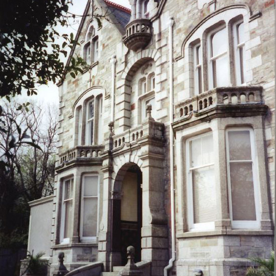 A photo of the front of a large house with two bay windows either side of the door.