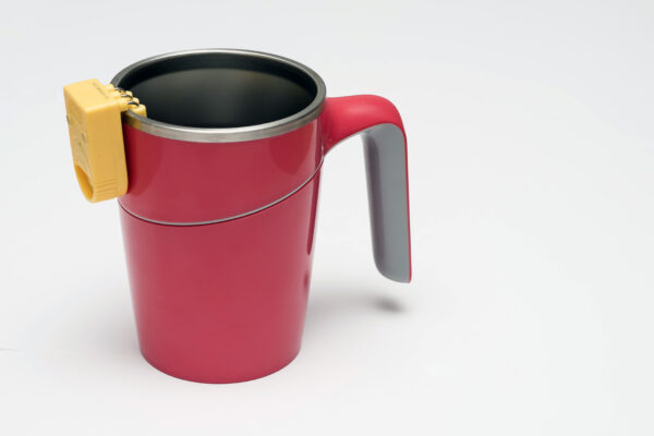 A tall cup with a handle with a liquid level indicator resting on the side