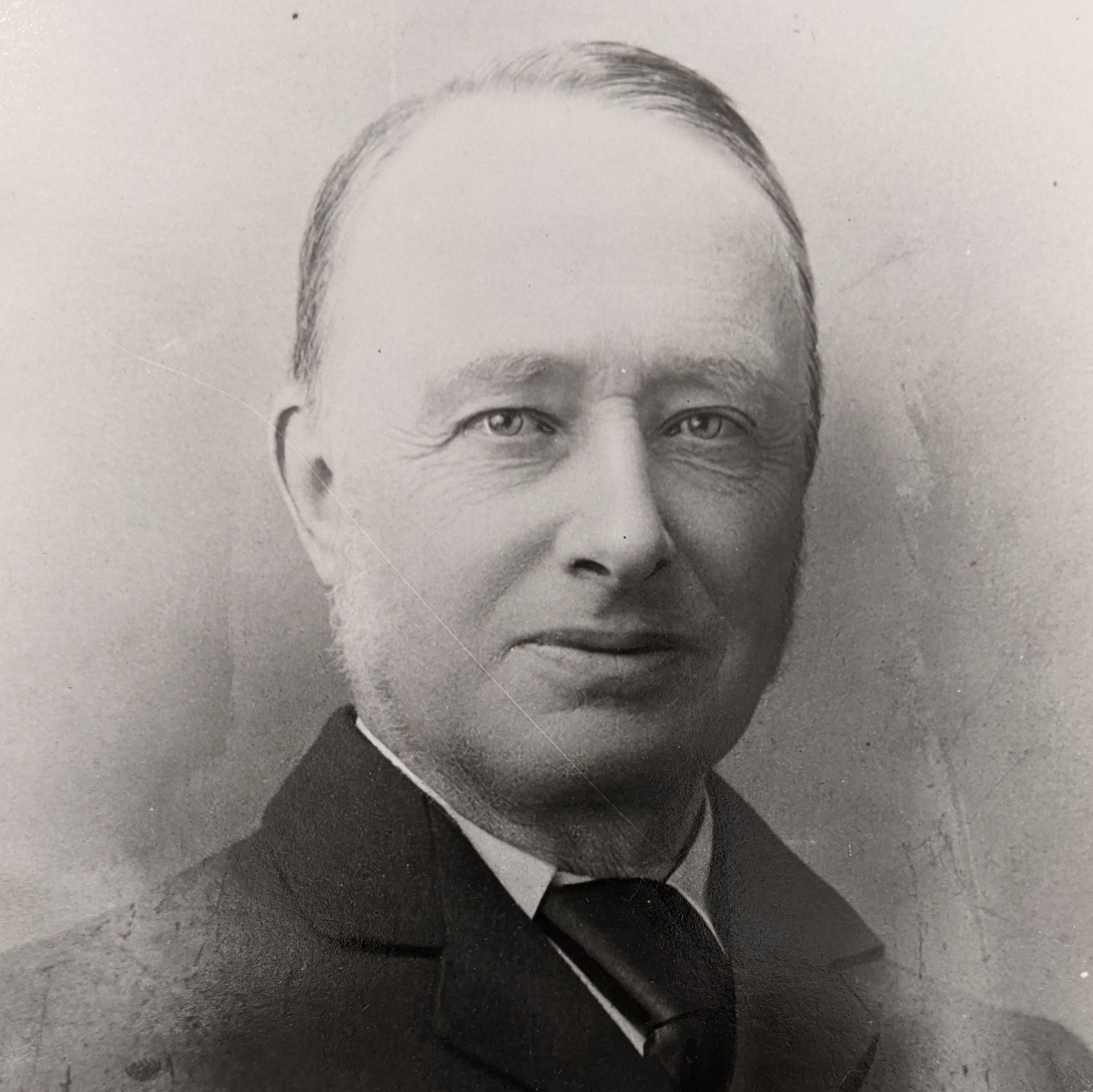 A black and white photograph of a man wearing a suit and tie.