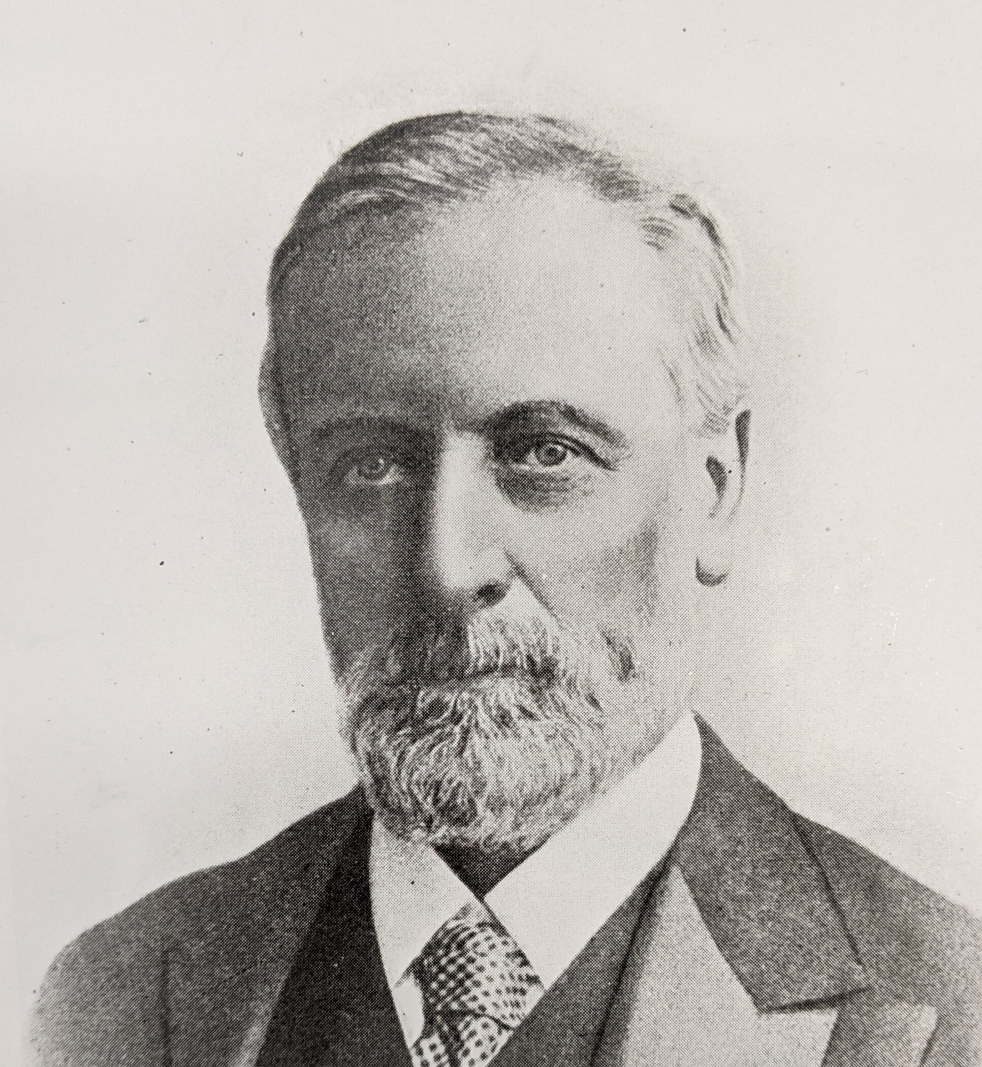 A black and white photograph of a gentleman with a beard in a suit