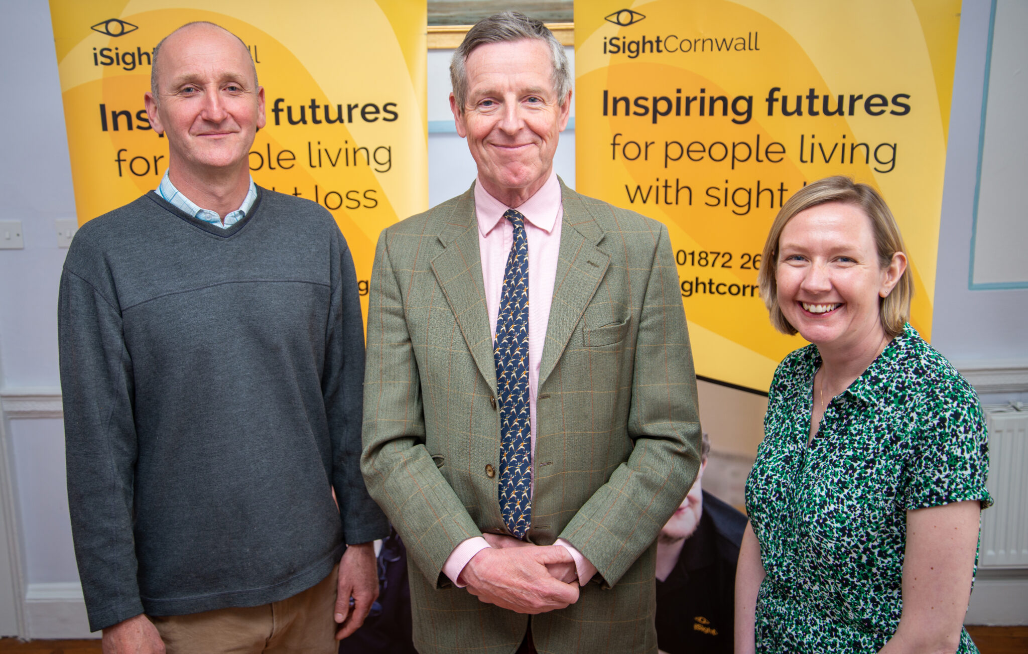 Two men and a woman standing in from of two iSightCornwall banners.