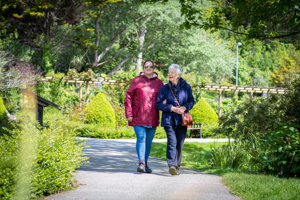 Two Ladies Walking Through The Park With Coats On