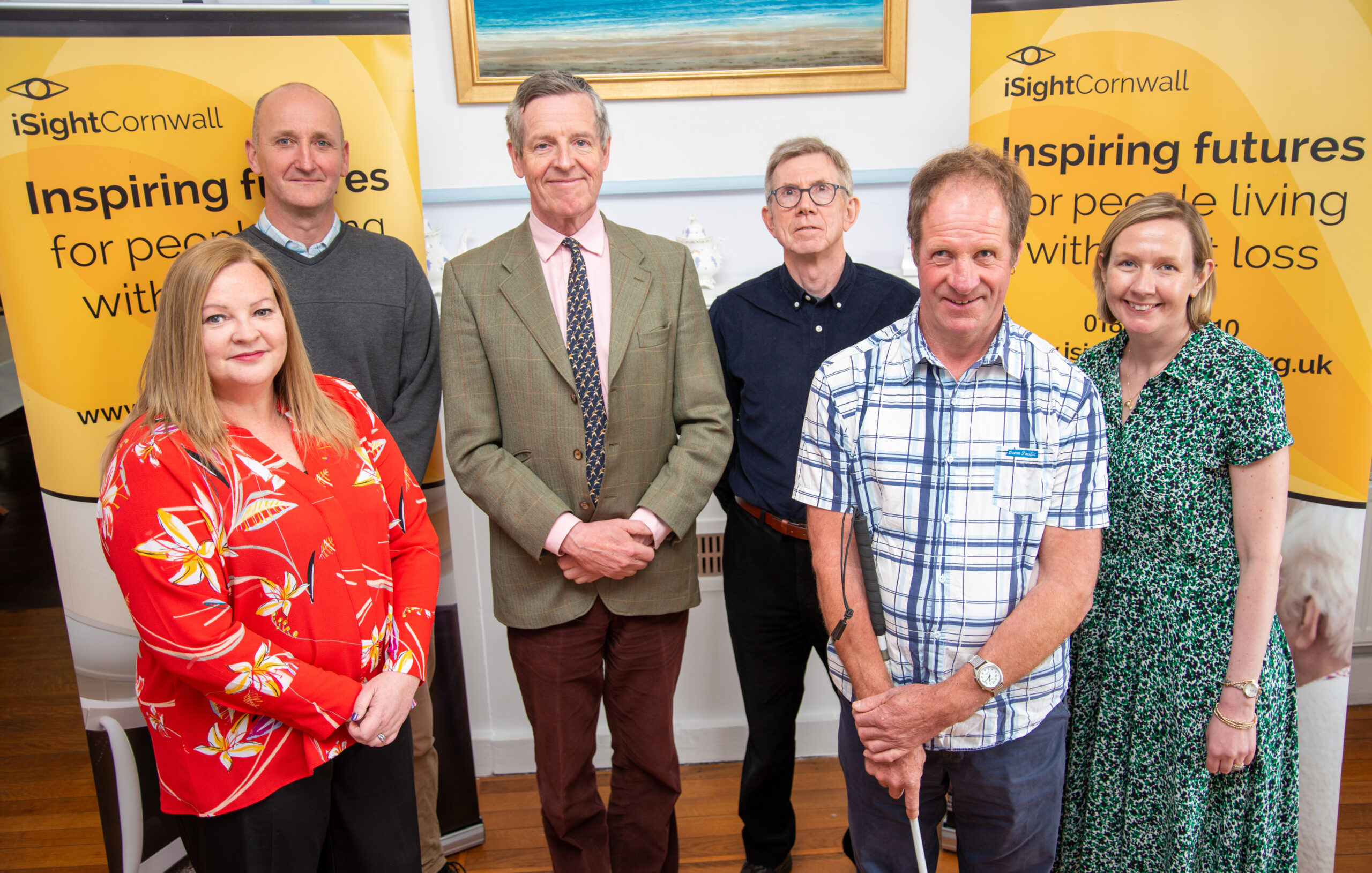 Six people standing in a line in front of two iSightCornwall banners.