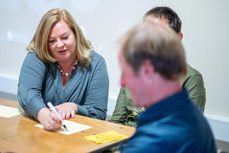 Lady In Grey Shirt Showing Somebody Where To Sign A On A Piece Of Paper