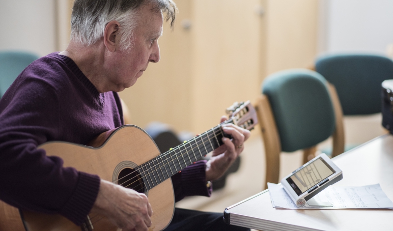 Man Playing Guitar Using Hd Magnifier