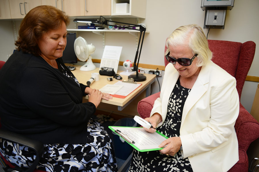 Woman Being Shown How To Use Handheld Magnifier