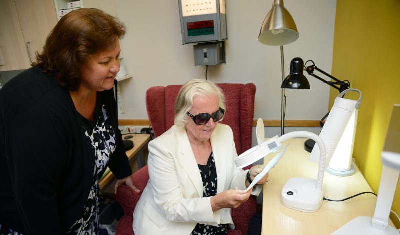 Women Using Desktop Magnifier To Read Document